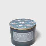Dark gray scented candle with blue cat lid pattern and 'Sand + Paws' label