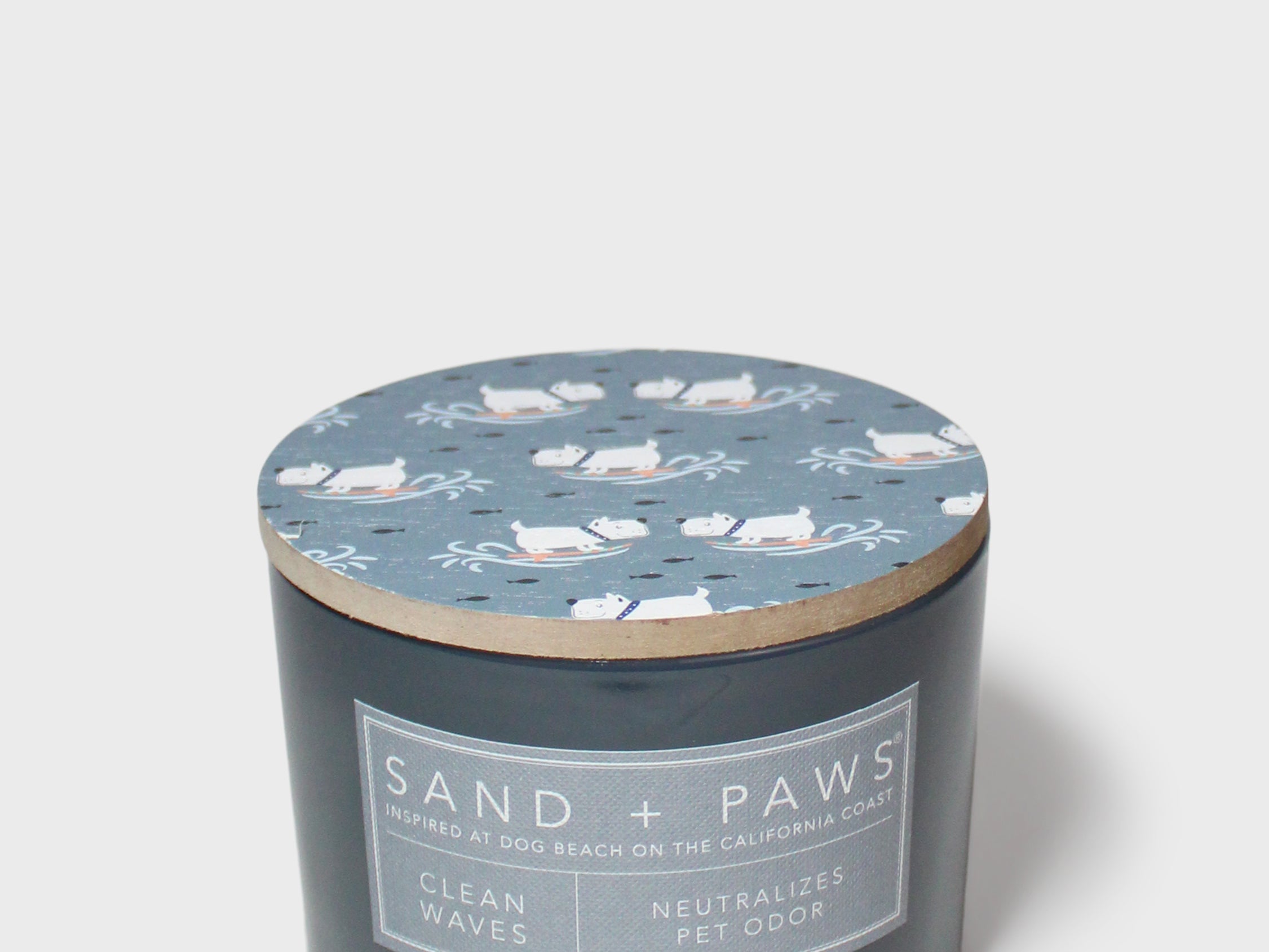 Dark gray scented candle with blue cat lid pattern and 'Sand + Paws' label