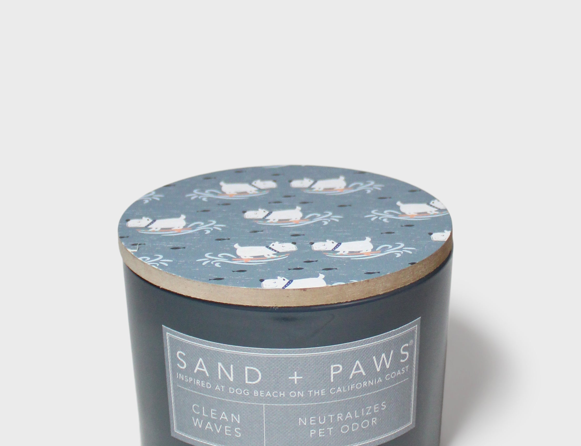 Dark gray scented candle with blue cat lid pattern and 'Sand + Paws' label
