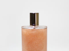 Illuminating body oil bottle with amber shimmer and gold pump cap