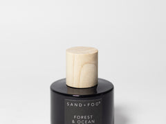 Perfume oil rollerball bottle with black label and wooden roller cap, 1.7 fl oz SAND+FOG.
